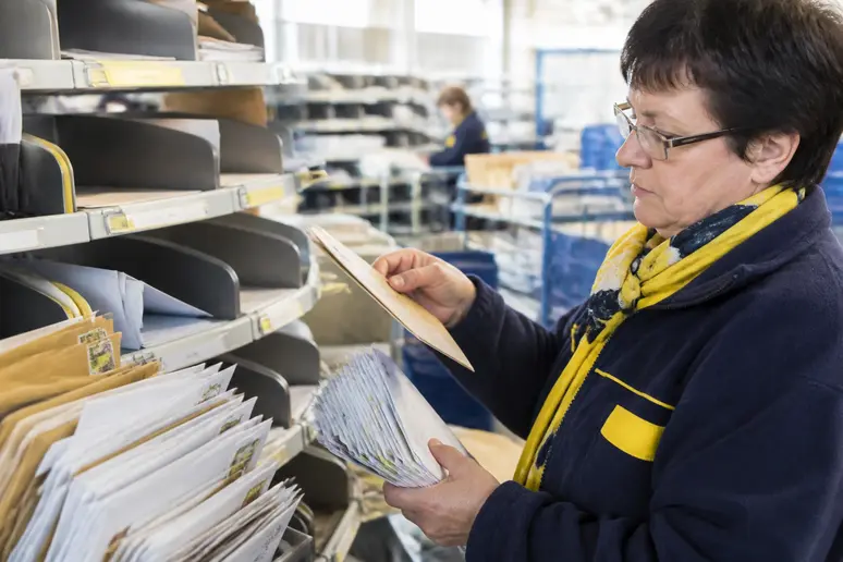 Facteur triant le courrier et les codes postaux de Cherbourg dans un centre de distribution
