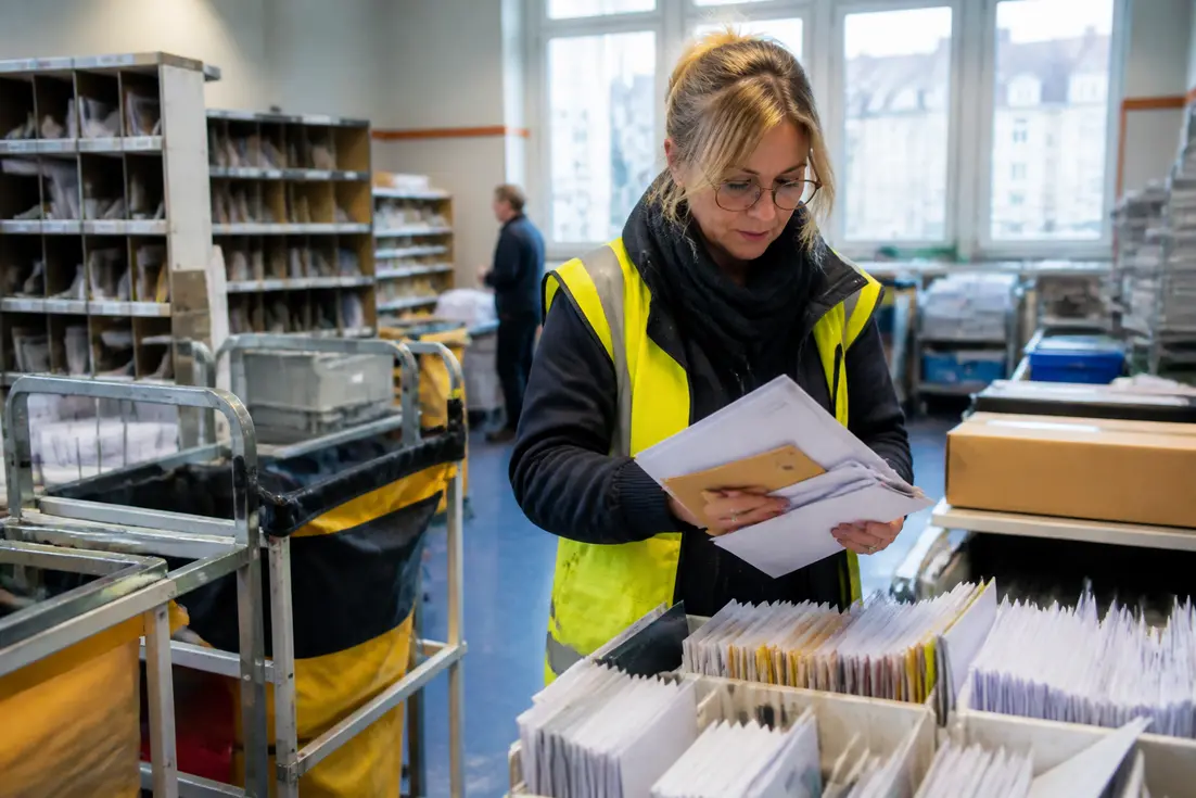 Un facteur en gilet de haute visibilité trie le courrier avec Dieppe code postal dans un bureau de poste local.