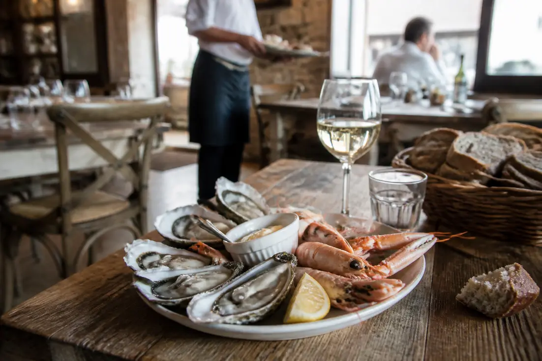 Un plateau de fruits de mer frais et un verre de vin blanc dans un dive sur mer restaurant en Normandie.
