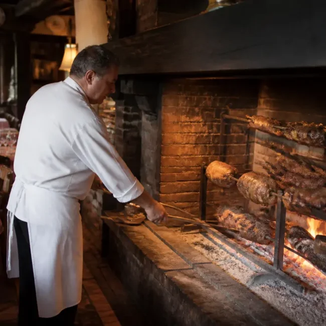 Un chef cuisine des viandes à la broche dans la cheminée de la maison de blonville en Normandie