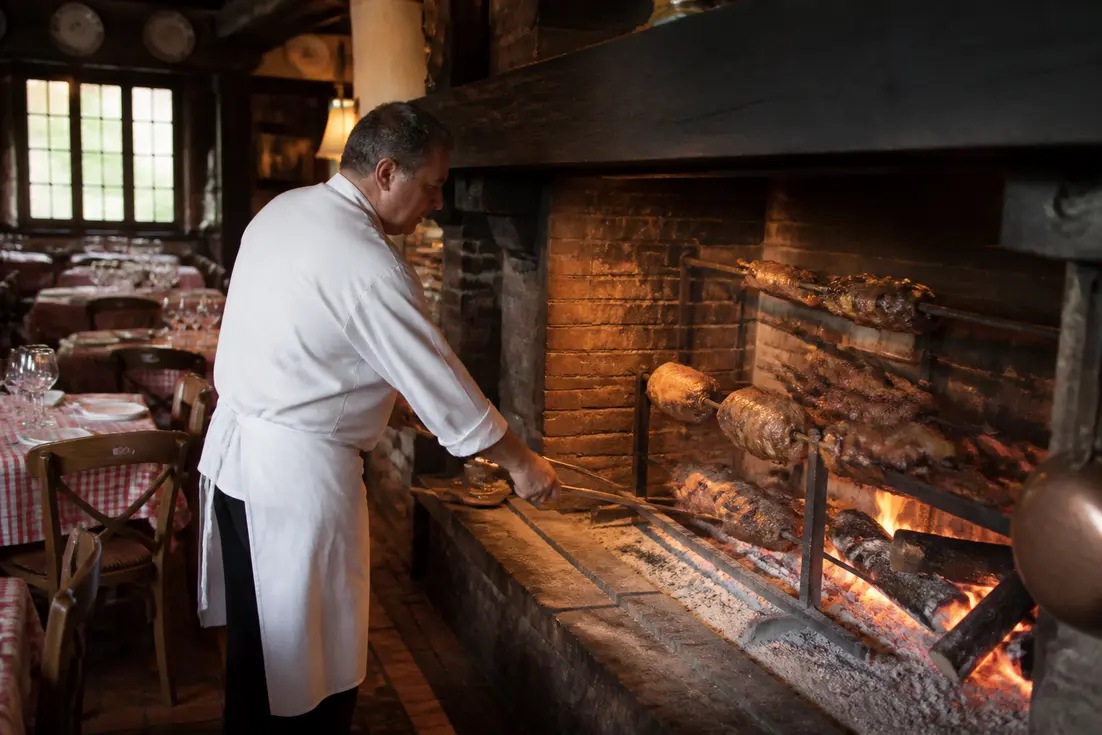 Un chef cuisine des viandes à la broche dans la cheminée de la maison de blonville en Normandie