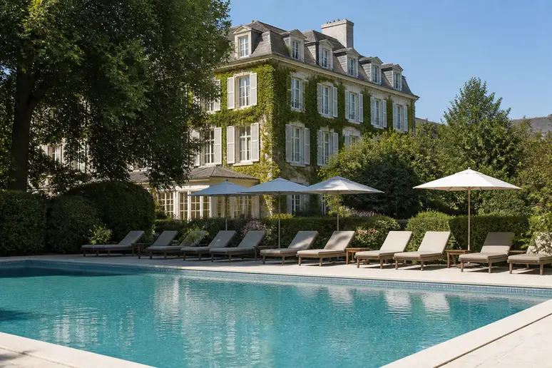Piscine extérieure et chaises longues dans le parc verdoyant d'un hôtel de charme en Normandie