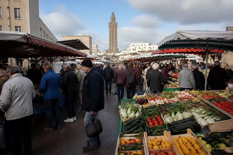 Étal de marché de plein vent avec des fruits et légumes frais sur une place animée