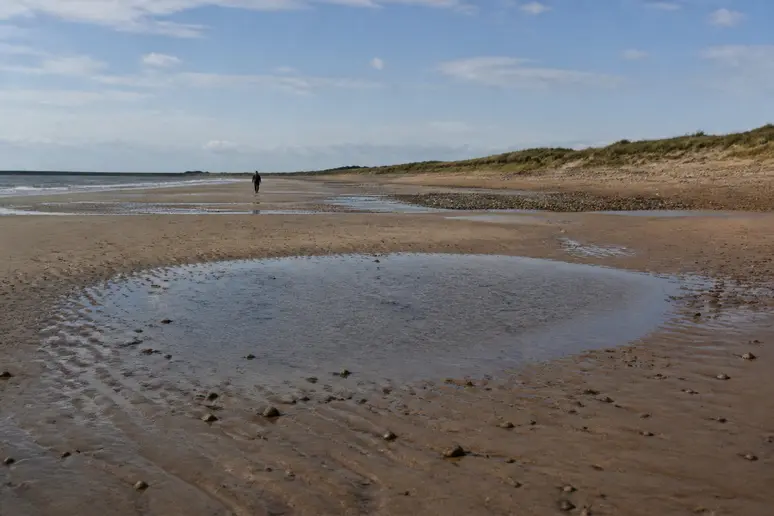 Immense plage de sable fin découverte à marée basse le long de la côte normande