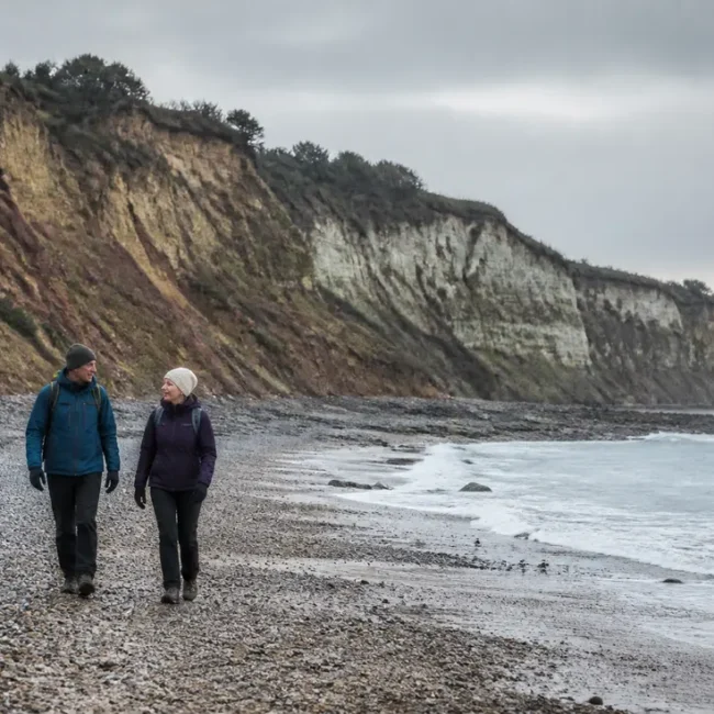 Randonneurs sur les galets pour visiter Villerville plage face aux falaises des Roches Noires.