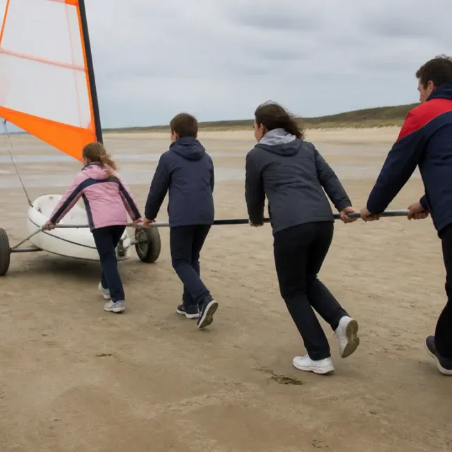 Une famille en vêtements de saison prépare son char à voile prix plages sur le sable.