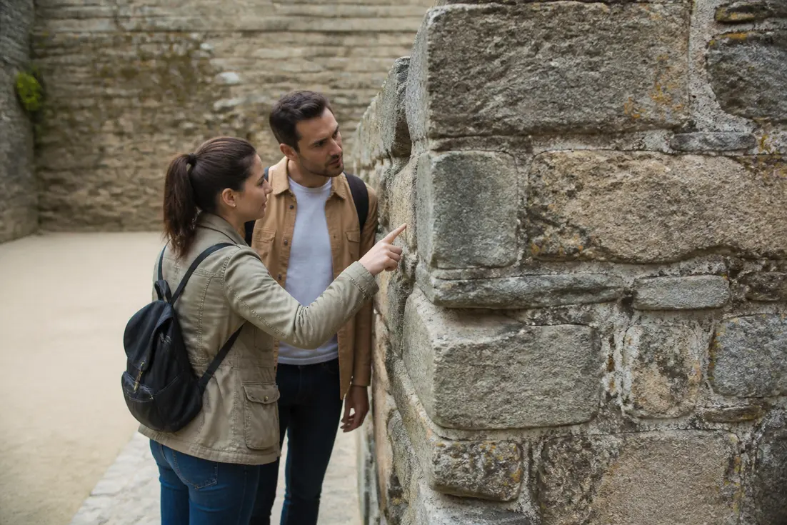 Un couple de voyageurs explore un site historique lors d'un circuit médiéval Normandie petit budget.