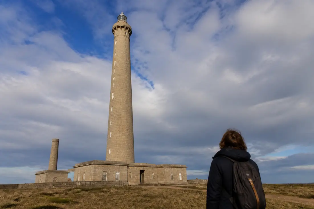 Visiteur observant la façade en pierre lors de ses Gatteville le Phare conseils visite en Normandie