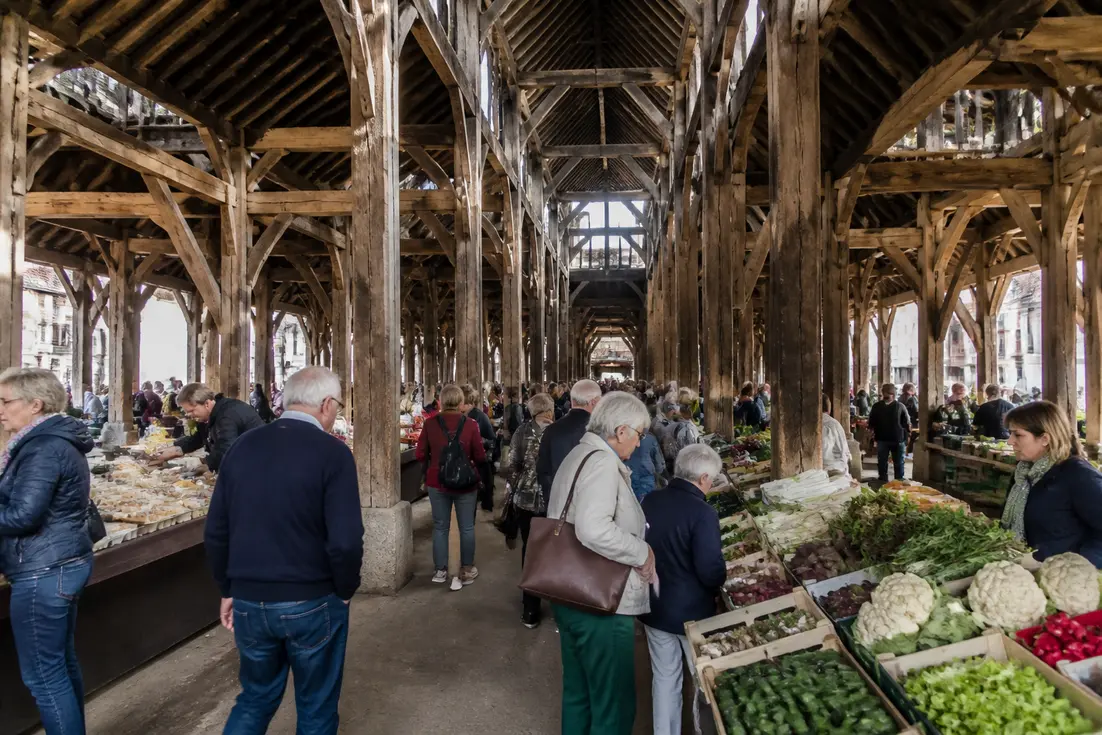 Ambiance animée sous les halles médiévales de Dives-sur-Mer lors du marché fermier du samedi matin