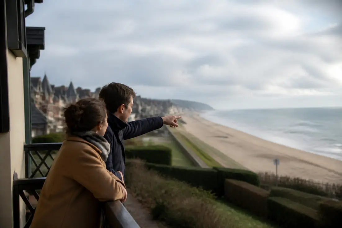 Voyageur sur un balcon face à la mer pour choisir hôtel Blonville-sur-Mer plage commerces en Normandie.