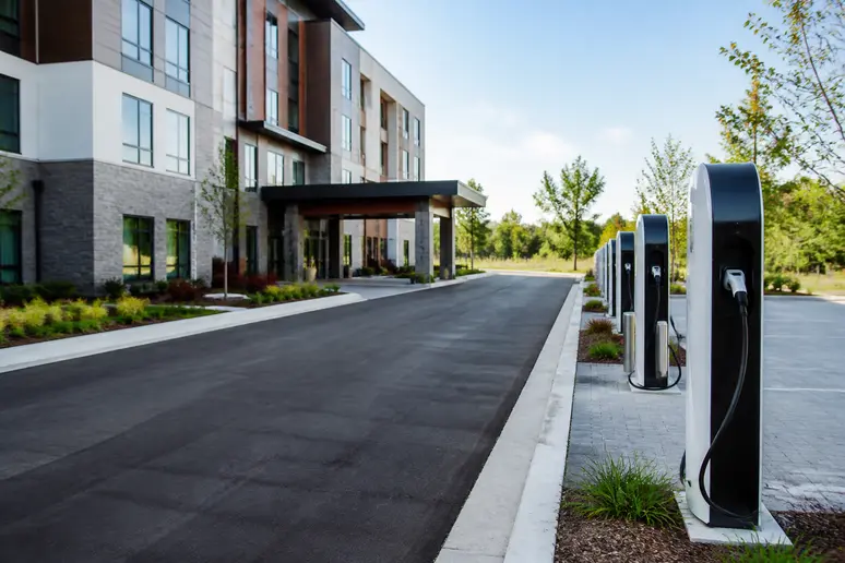 Borne de recharge pour véhicule électrique installée sur le parking extérieur sécurisé d'un hôtel