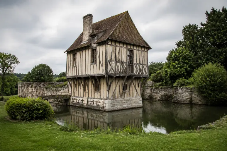Manoir normand à pans de bois entouré de ses douves en eau dans le Pays d'Auge.