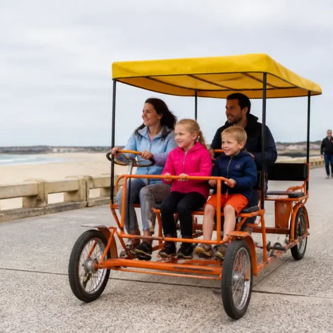 Une famille pédale ensemble sur une rosalie en bord de mer pour connaître le prix location rosalie bord de mer.