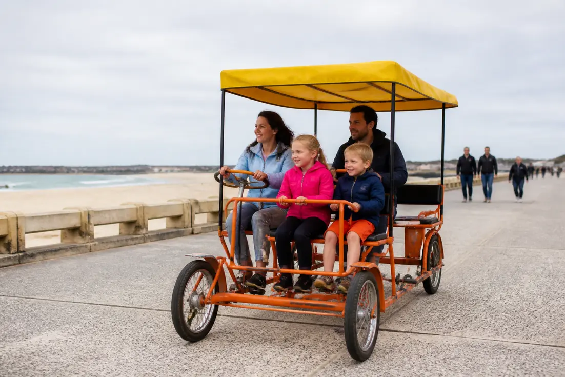 Une famille pédale ensemble sur une rosalie en bord de mer pour connaître le prix location rosalie bord de mer.