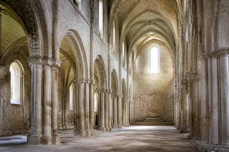 Intérieur de l'église abbatiale montrant les voûtes gothiques et les piliers anciens en pierre.