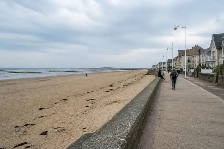 Randonneur marchant sur l'itinéraire de Sword Beach le long de la digue côtière