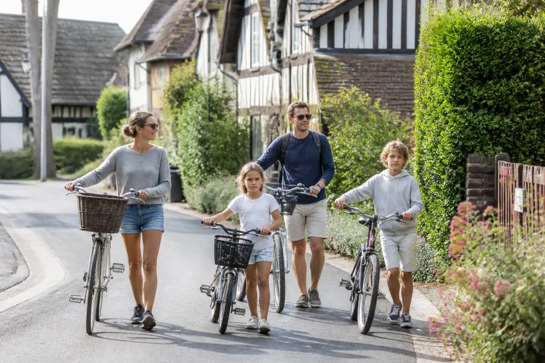 Une famille se promène à vélo pour des locations vacances Varaville été près des maisons normandes.
