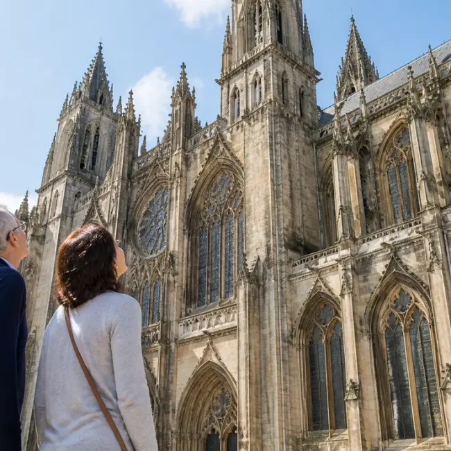 Touristes admirant la magnifique architecture normande lors de leur Visiter Cathédrale Notre-Dame de Bayeux un après-midi ensoleillé