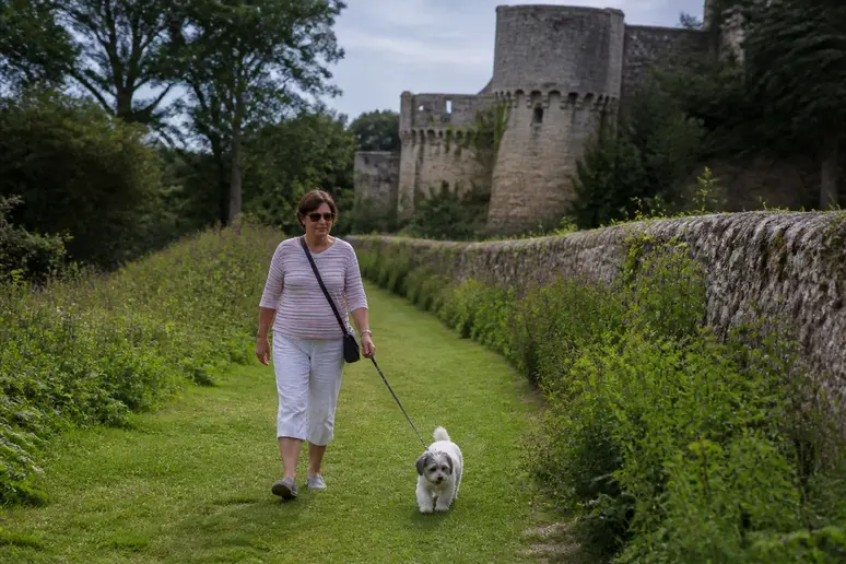 Visiteur promenant son chien en laisse dans les allées des Jardins du Pays d'Auge