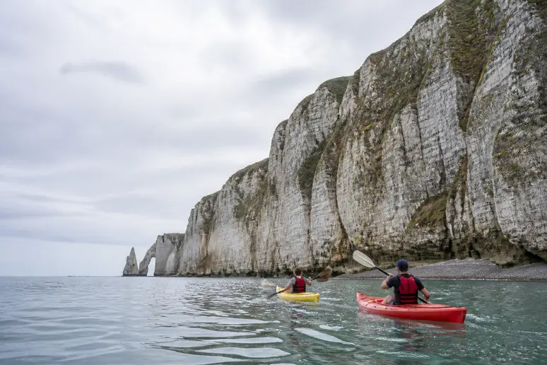 Kayakeurs naviguant au pied des falaises de craie blanche et des arches marines