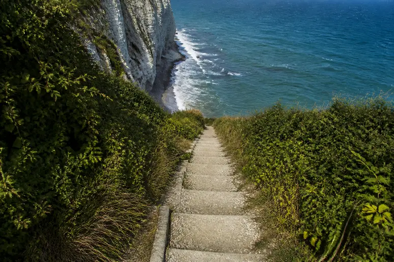 Sentier escarpé creusé dans la craie menant vers la mer le long des falaises.